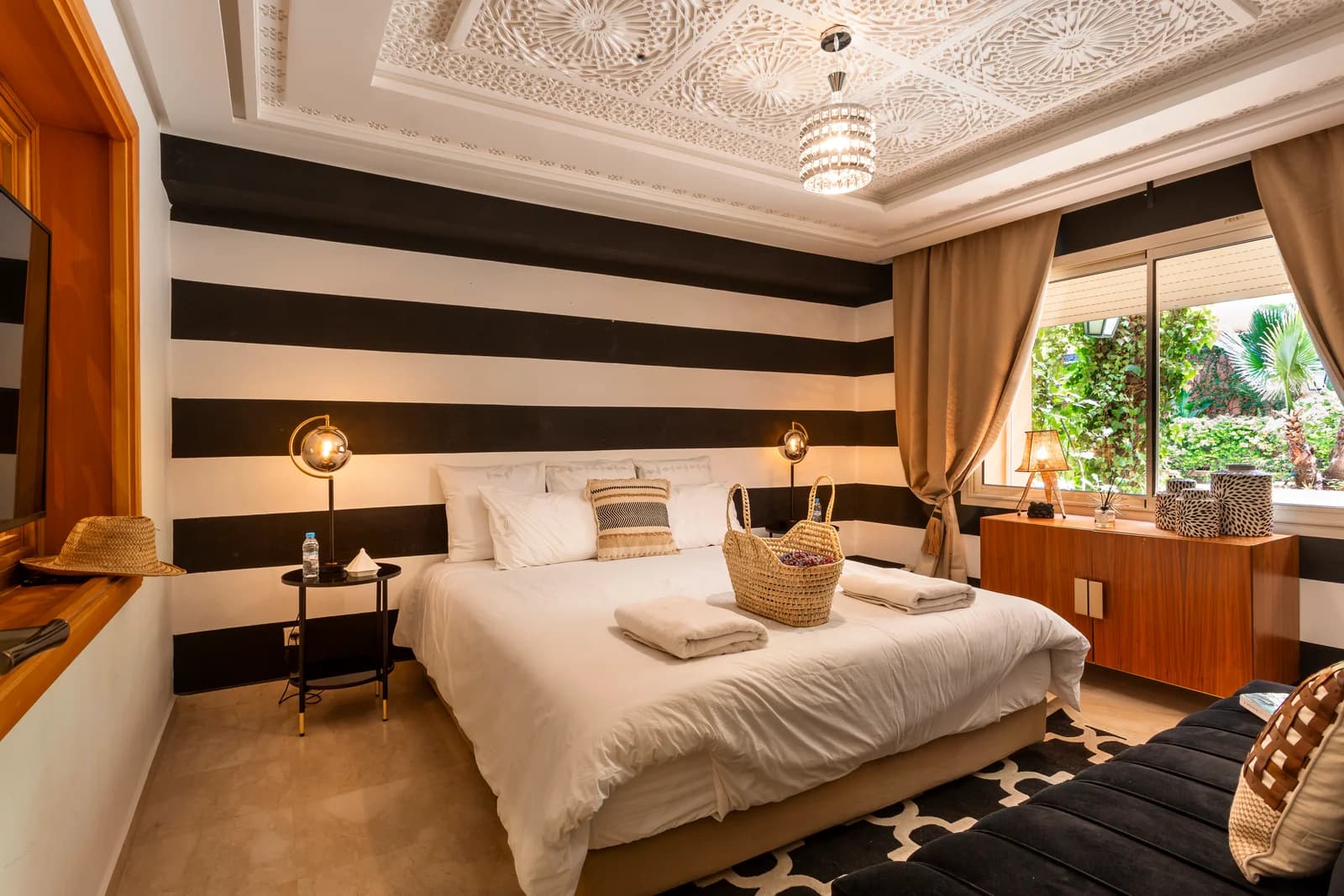 King bed framed by stripes beneath intricately carved white ceiling