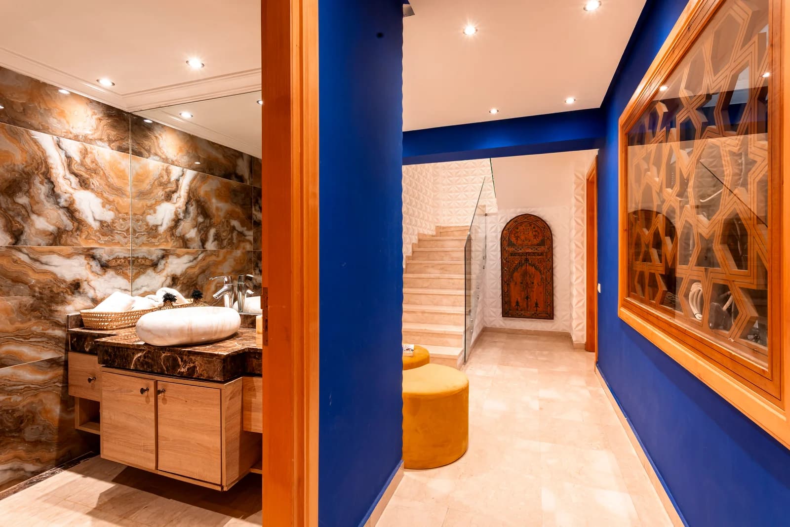Cobalt corridor with carved Moroccan door and travertine staircase