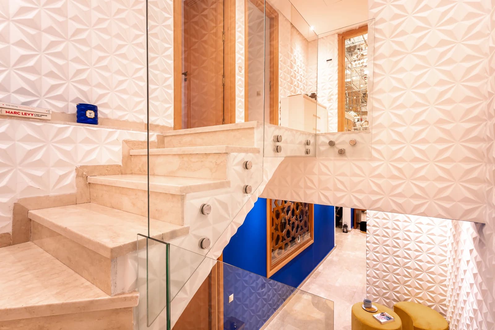Sculpted 3D wall panels framing travertine stair and zellige niche