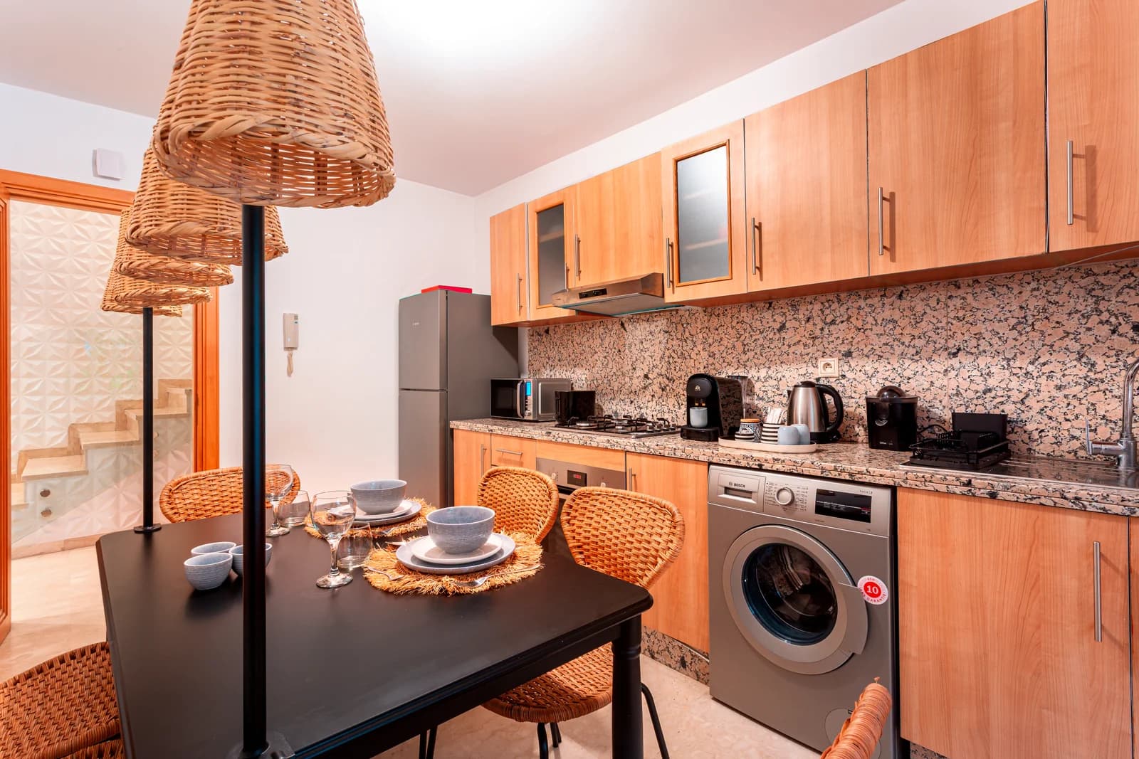 Compact wood-toned kitchen with rattan pendants and breakfast table