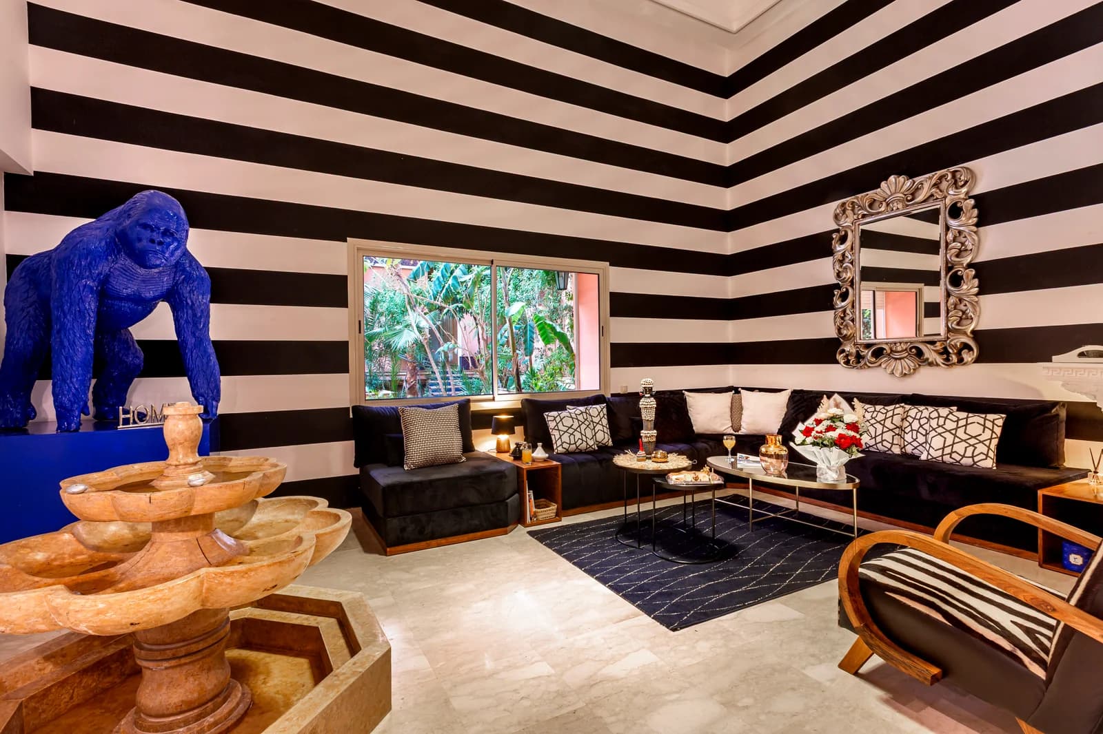 Striped salon with blue gorilla sculpture and ornate silver mirror