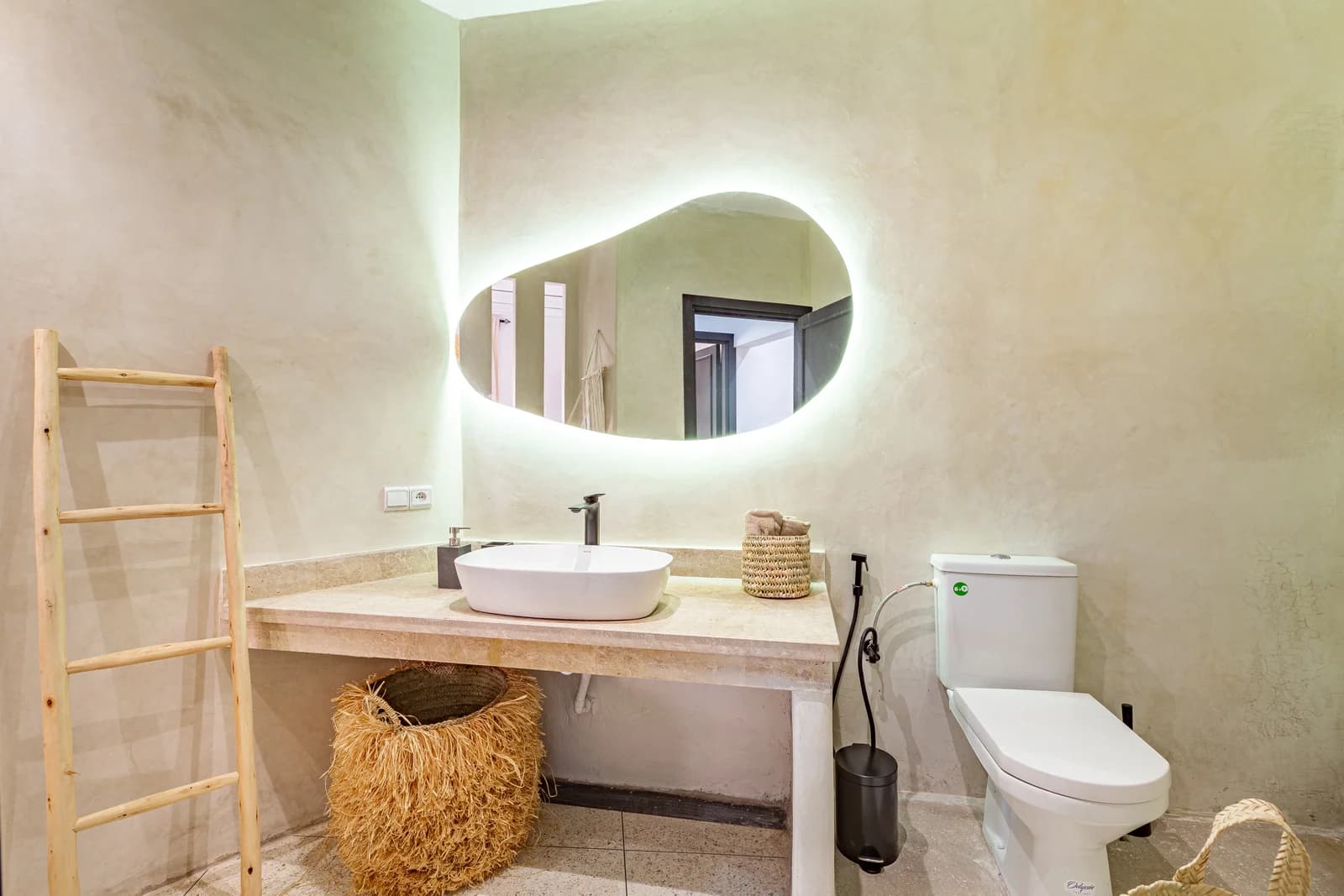 Sculpted organic mirror over vessel sink in tadelakt-finished bath