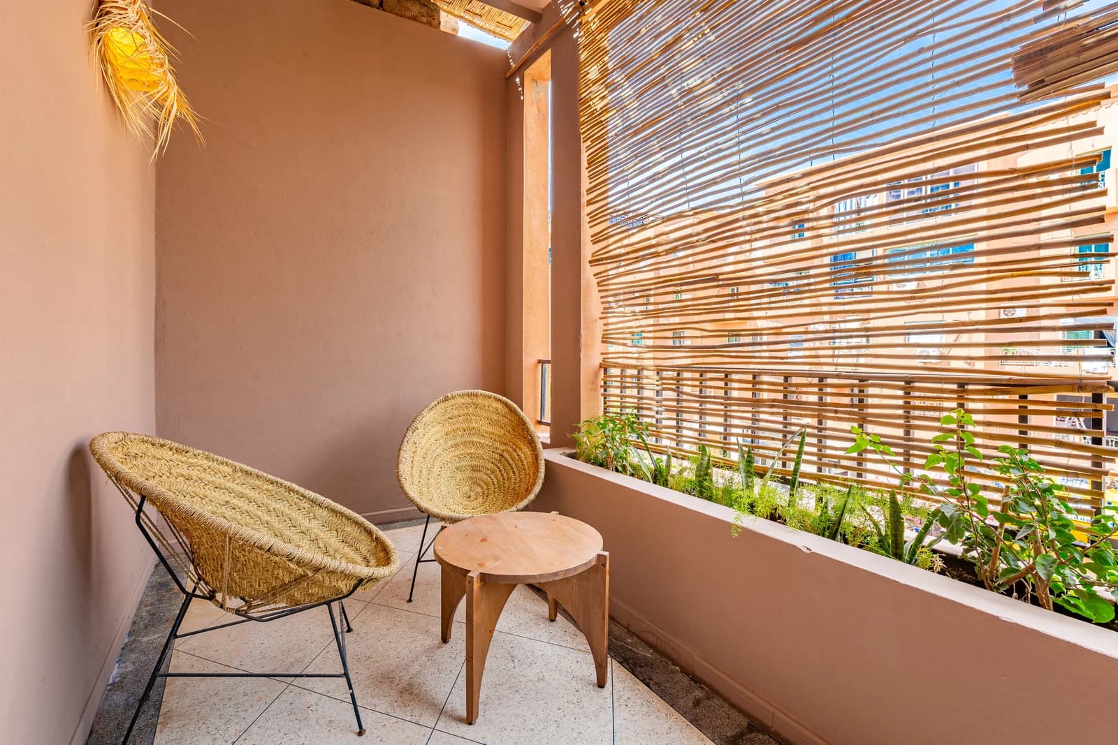 Woven rattan chairs on the terracotta balcony beside potted herbs
