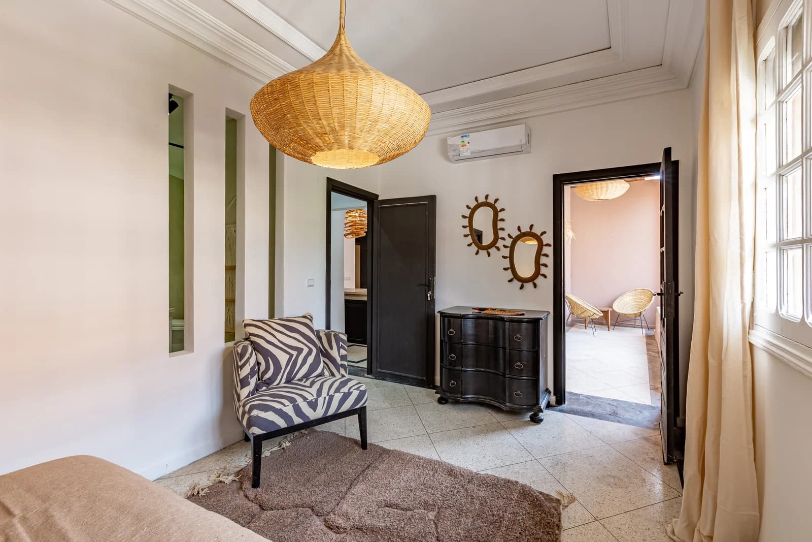 Antique chest and zebra chair under woven pendant in entry