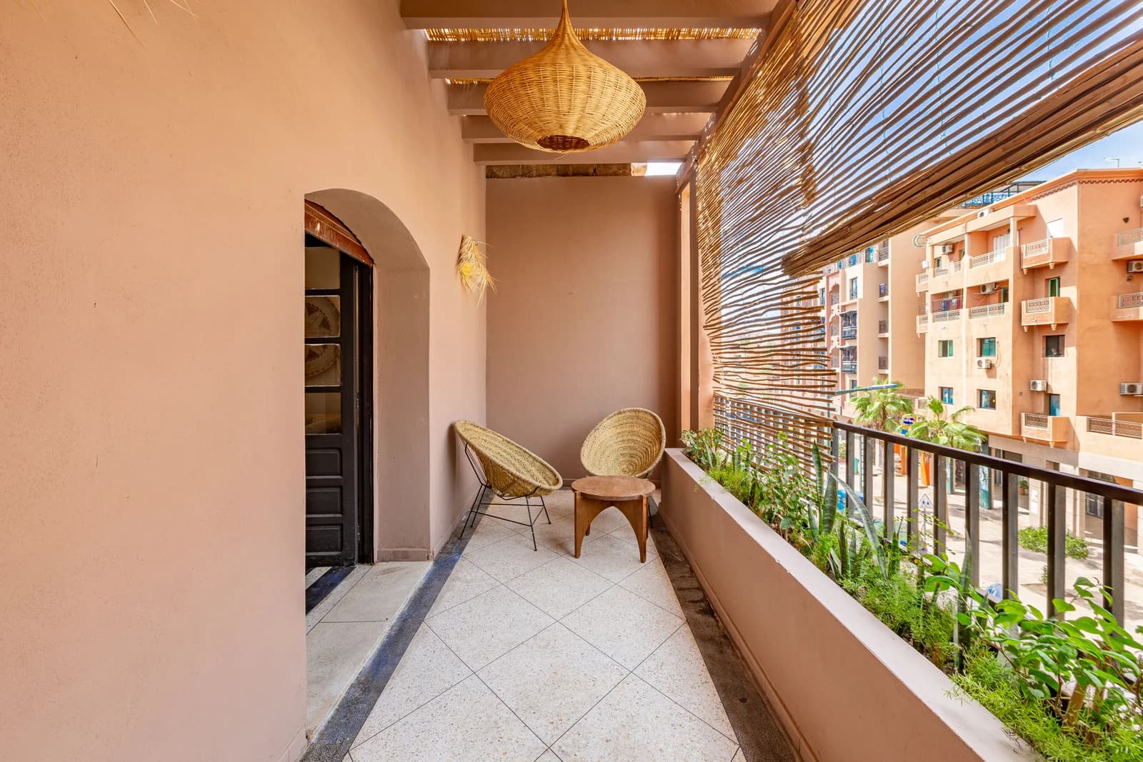 Terracotta balcony with rattan pendants, bamboo screen and city view