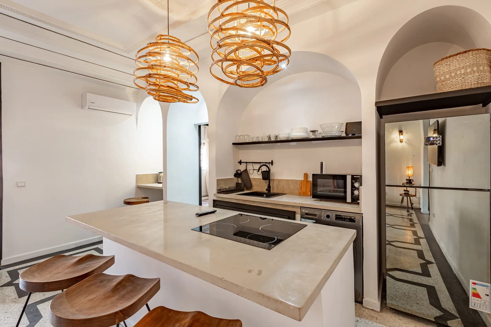 Vaulted kitchen with arched openings, stone counter and rattan pendants