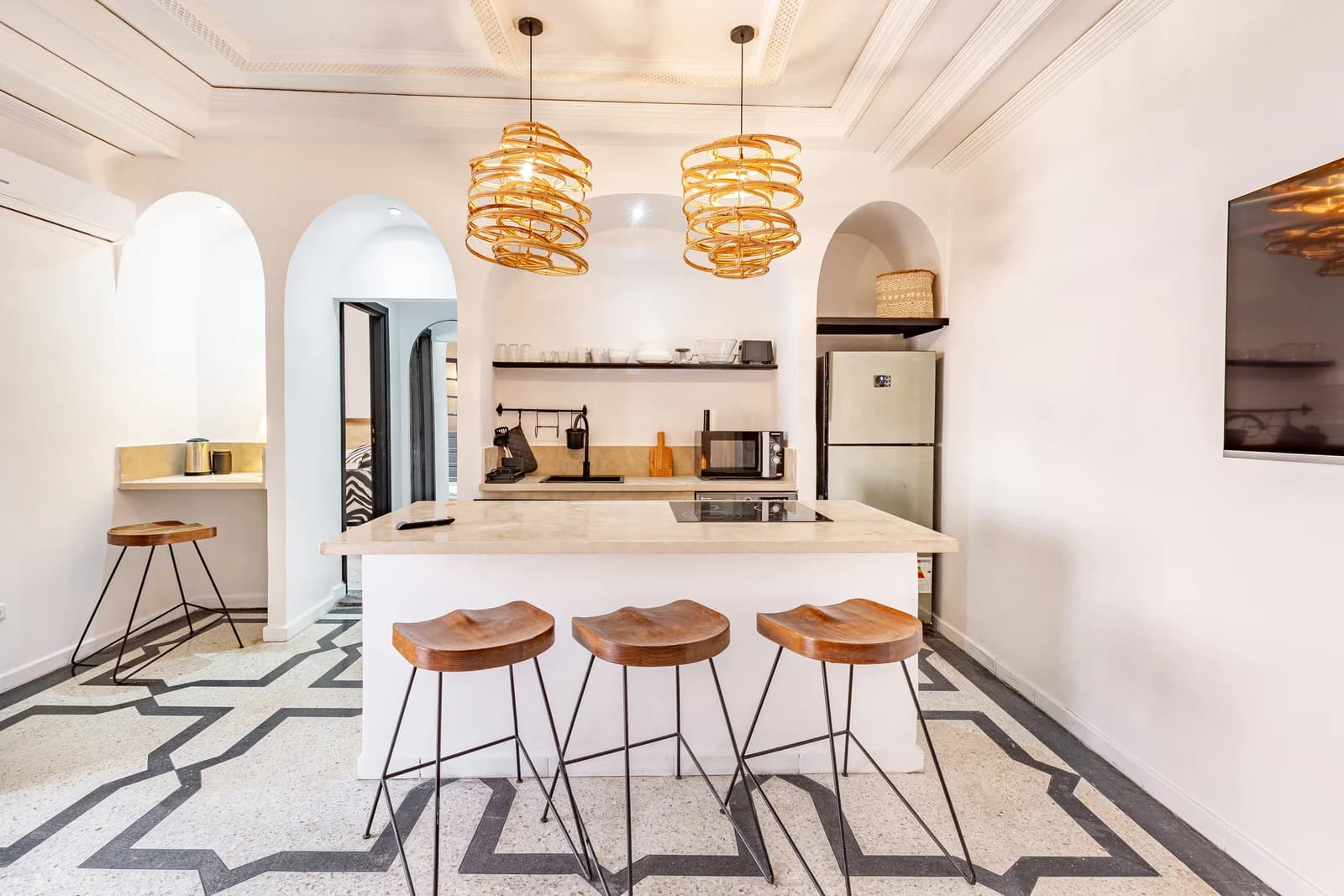 Whitewashed kitchen island under sculptural rattan pendants