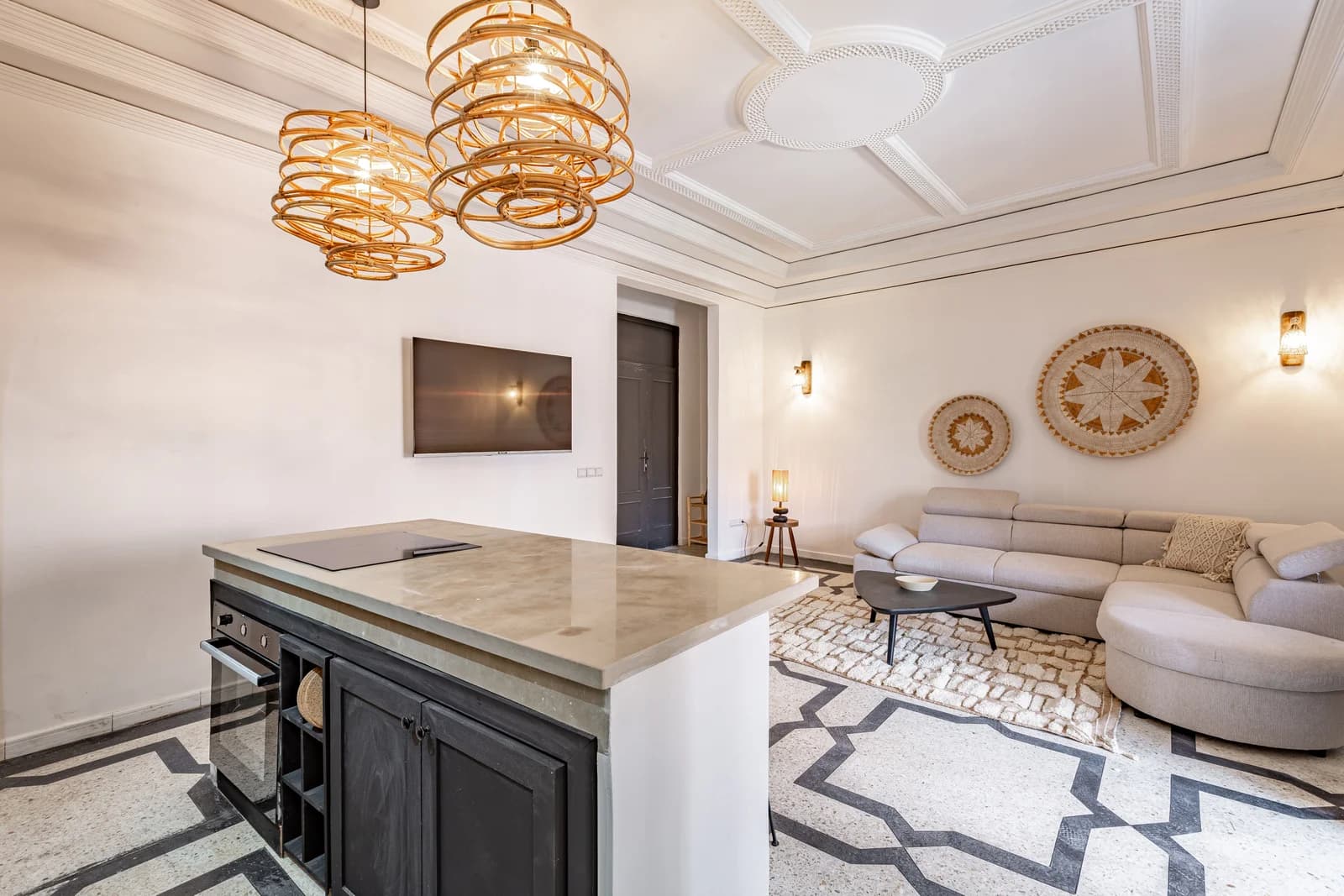 Lounge anchored by rattan chandeliers and hand-laid tile rug
